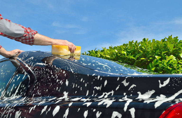 person using sponge to wash car