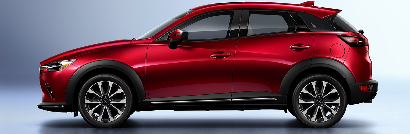 Side view of a red 2019 Mazda CX-3 parked in a silver showroom