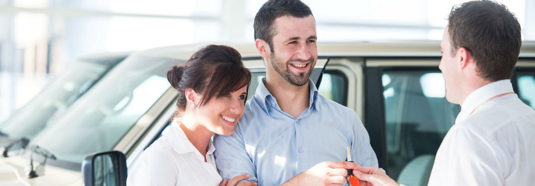 Smiling couple being handed keys to a car