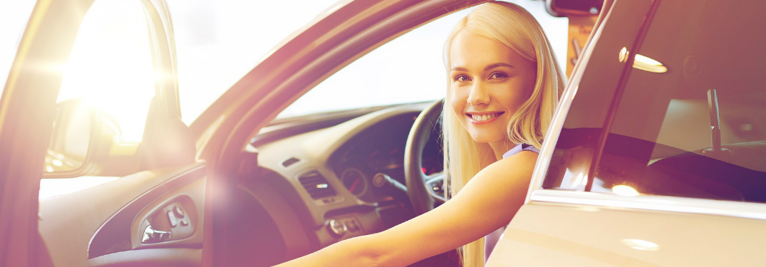Woman sitting in the front seat of a car with the door open