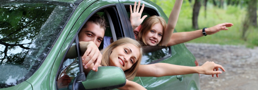 Group of friends waving from a green car