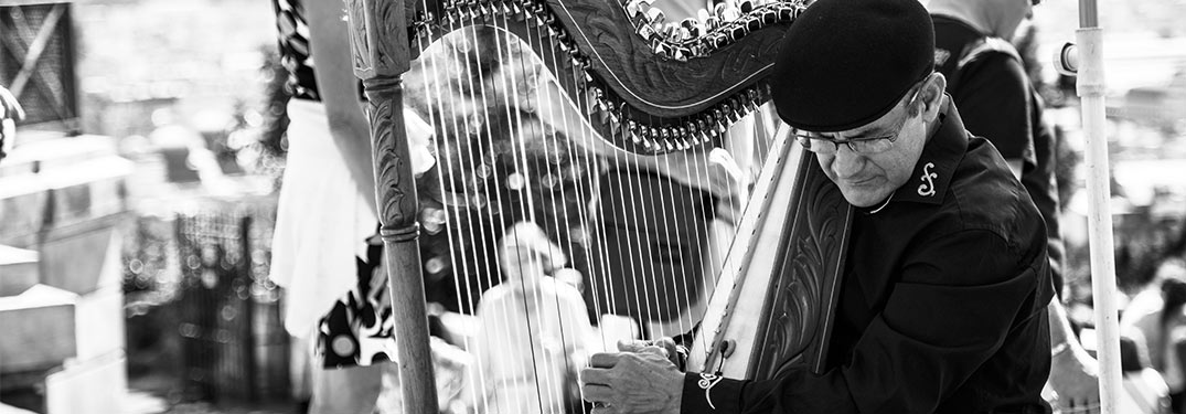 man playing harp in black and white