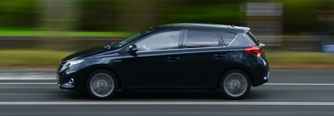 side view of black compact car driving