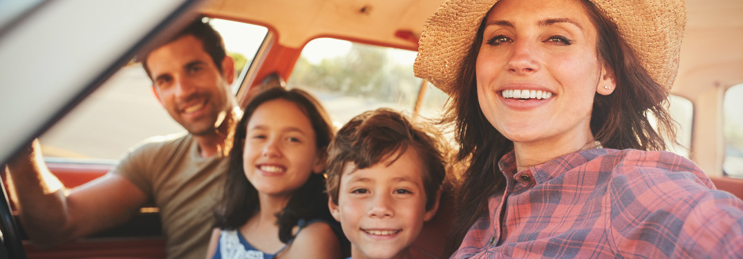 Family of four sitting in the front of their vehicle