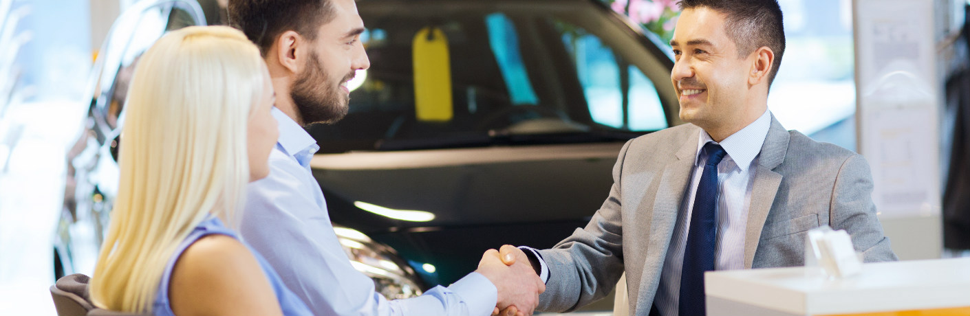 Couple shaking hands with a salesman at a dealership