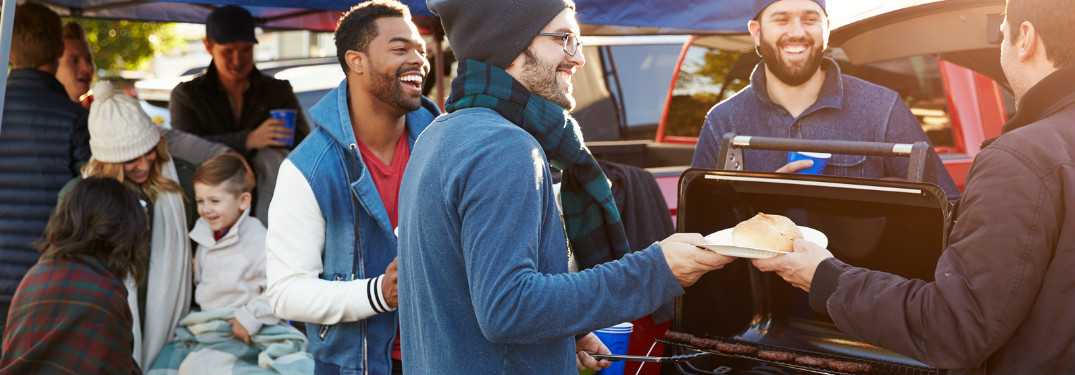 Group of tailgaters huddled around the grill