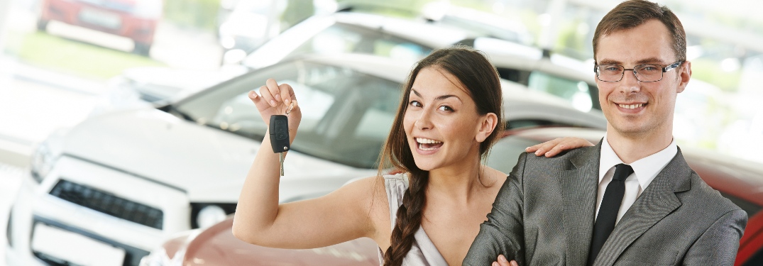 Happy couple with woman holding new car keys
