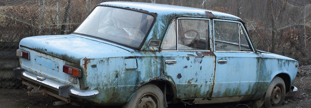 Rusty vehicle with leafless trees in background