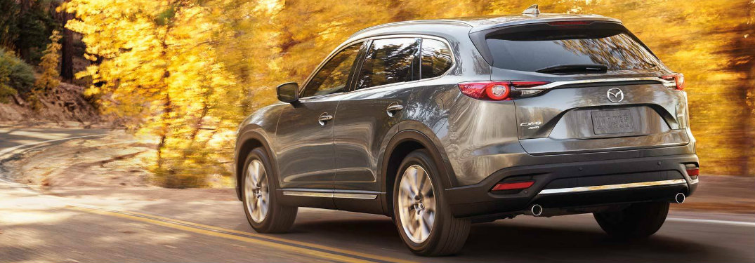 2019 Mazda CX-9 exterior rear view as it drives on highway surrounded by yellow leaves