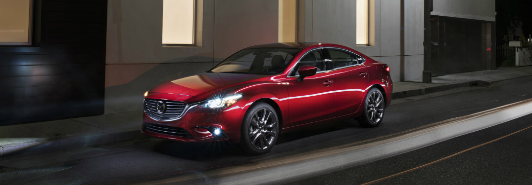 red 2018 mazda 6 driving past large concrete building