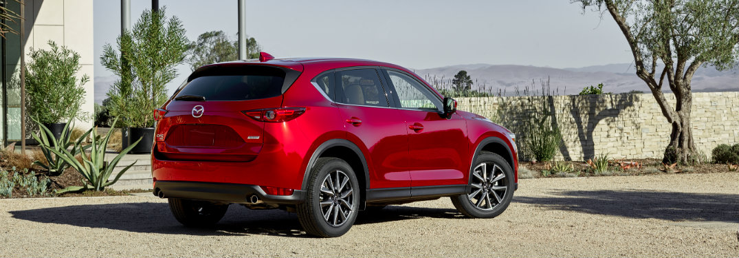 rear view of red 2018 mazda cx-5 on gravel driveway of modern home