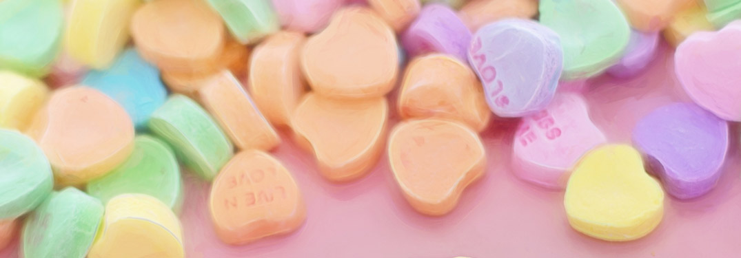 A pile of candy hearts over a pink background
