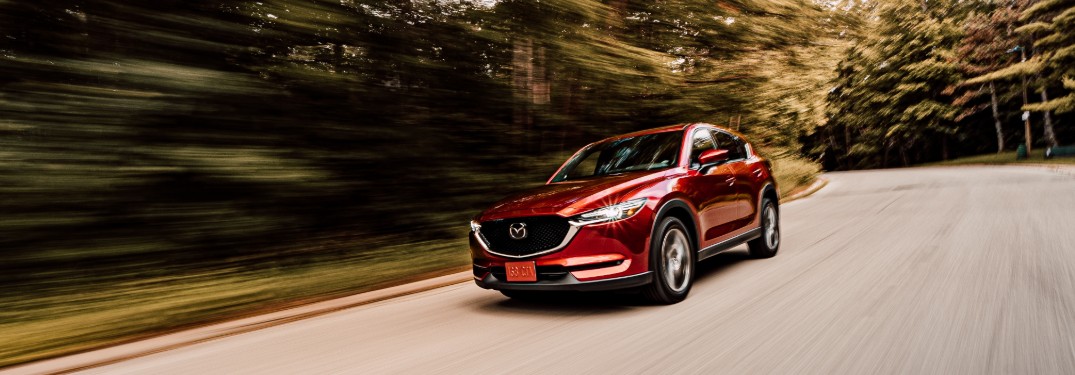 A red 2020 Mazda CX-5 driving quickly down a road.