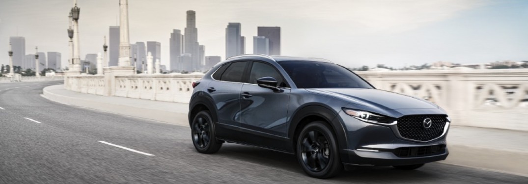 The side image of a gray 2021 Mazda CX-30 2.5 Turbo model driving away from a city.