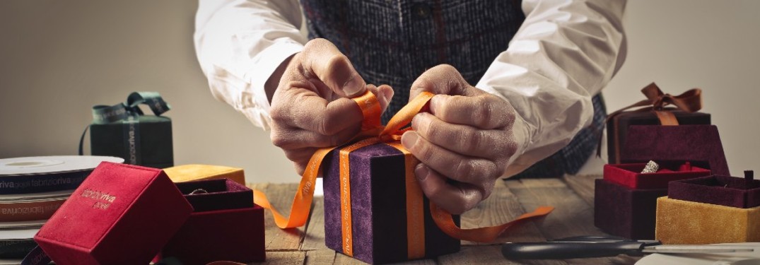 AN elderly man trying a bow to a present on a table.