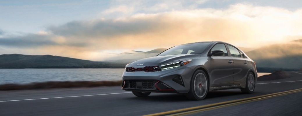 Side view of a 2022 Kia Forte cruising on a road.