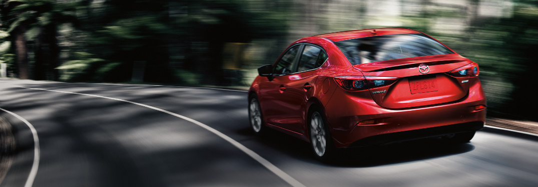 rear view of 2018 mazda3 driving on forest road under shadows