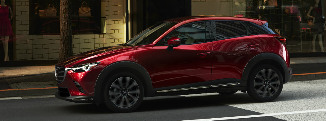 Profile view of red 2019 Mazda CX-3 parked in front of modern-styled building