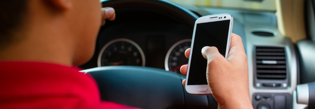 man holding phone while driving