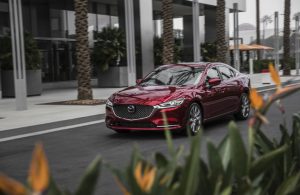 dark red mazda6 on road by flowers
