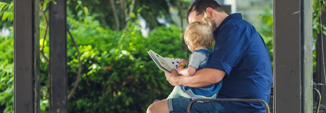 Father Reading to Daughter Outside