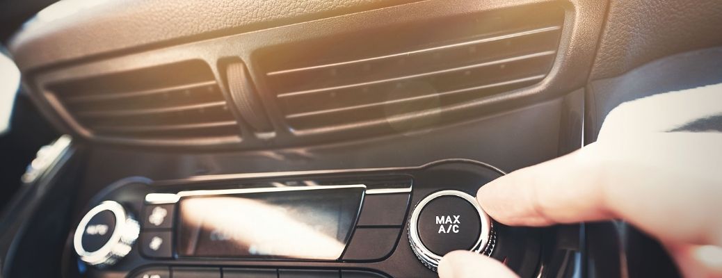 man's hand on the car air conditioning knob