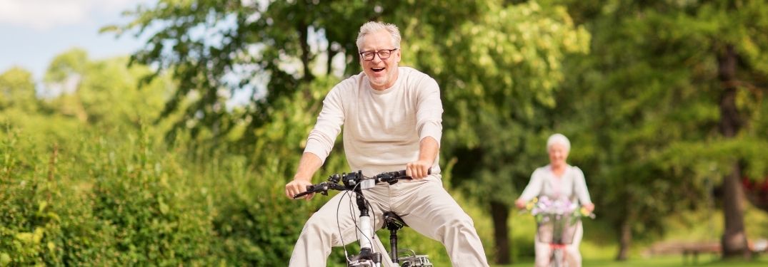 Old couple riding a bike in a park