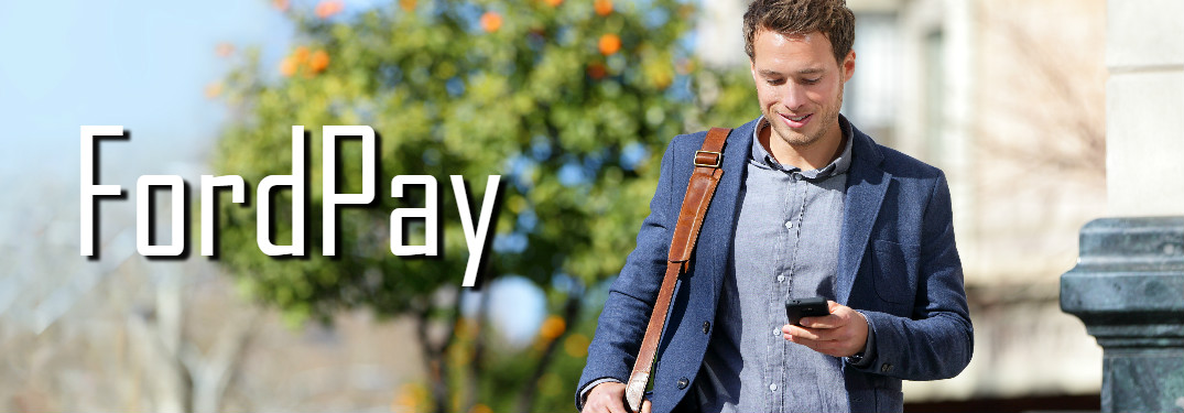 young businessman walking outside looking at phone on a sunny day