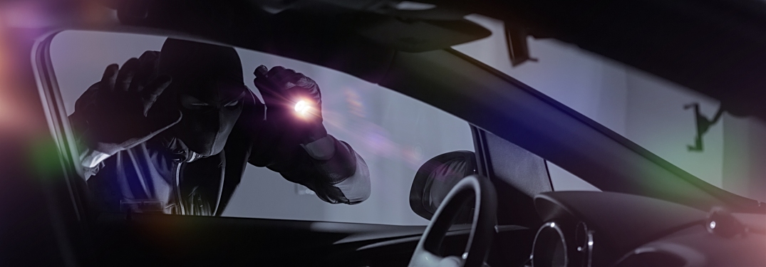 Thief peeking into a car with a flashlight at night