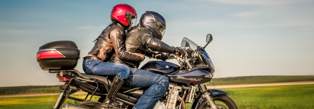 Two motorcyclists riding a blue bike side view with helmets