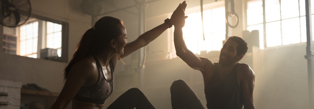 Man and woman high-fiving in gym after workout