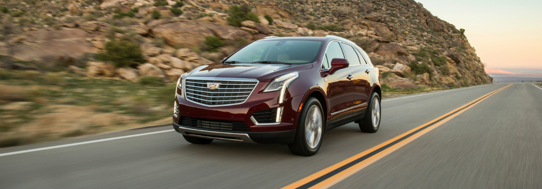 red 2018 cadillac xt5 driving on highway with desert mountains in background