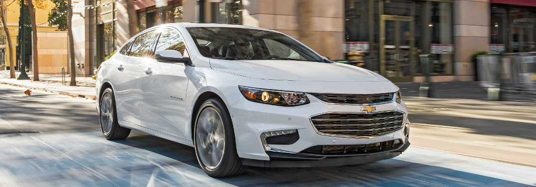 white 2018 chevrolet malibu driving through daytime city streets