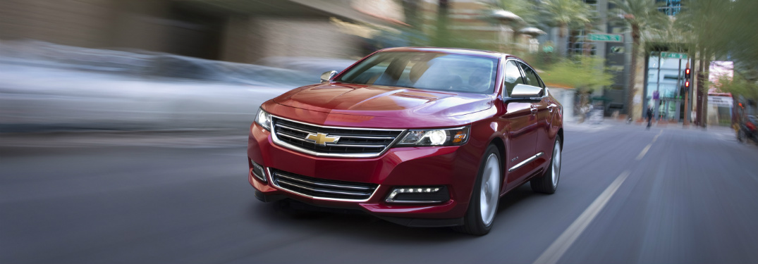red 2018 chevrolet impala driving through downtown city