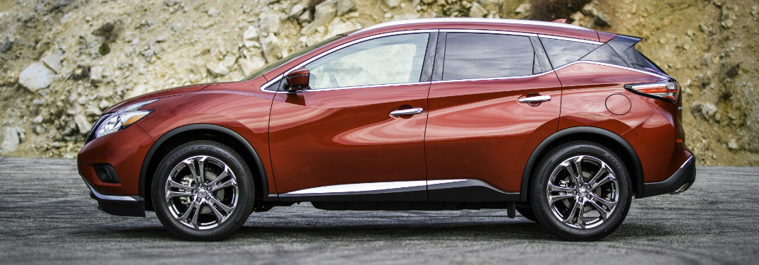 side view of orange 2018 nissan murano against mountain of rocks and dirt