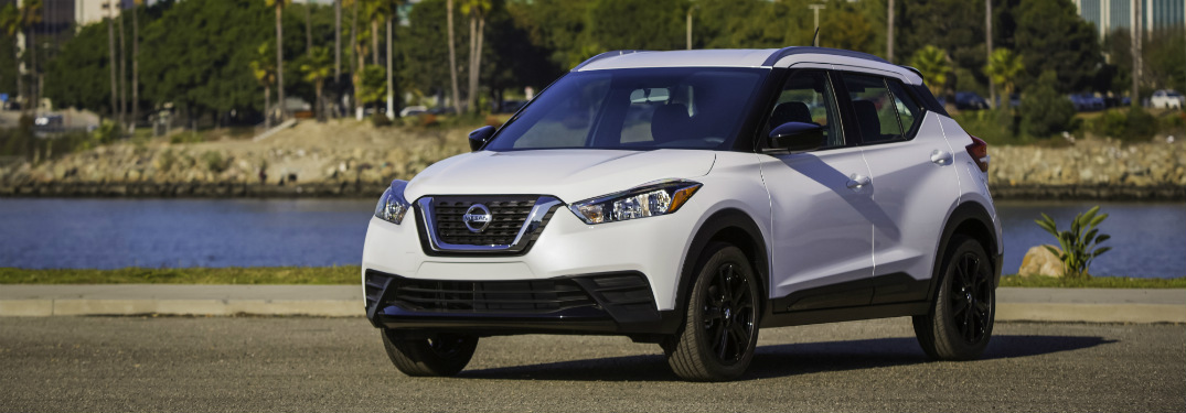 front and side view of white 2018 nissan kicks with river behind it