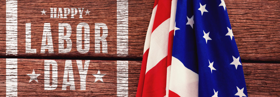 wooden board with "happy labor day" text on it next to american flag
