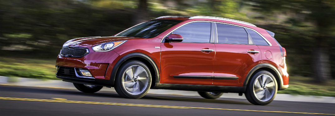 side view of red 2018 kia niro driving on road