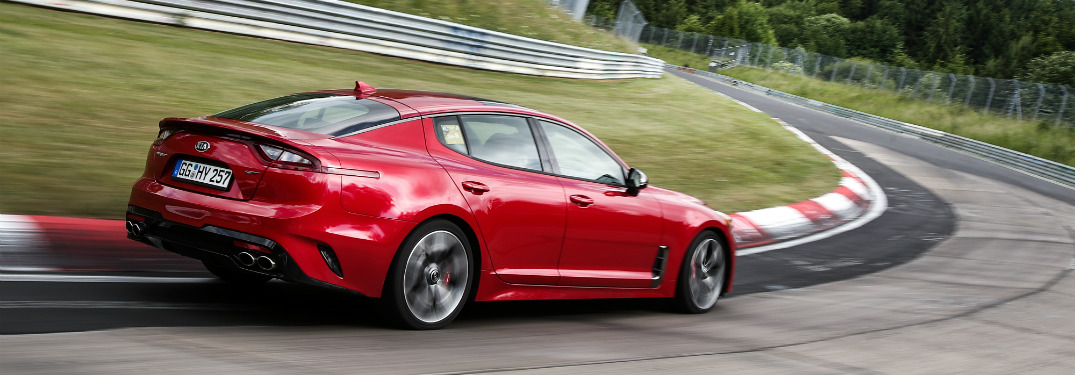 rear view of red 2018 kia stinger going around bend on professional race course
