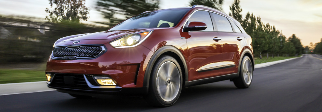 red 2018 kia niro driving on suburban road