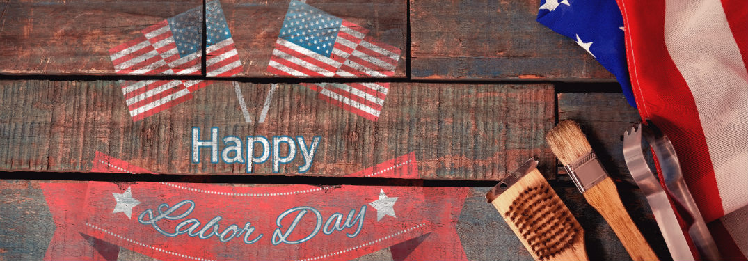 wood with labor day weekend art on it next to flag