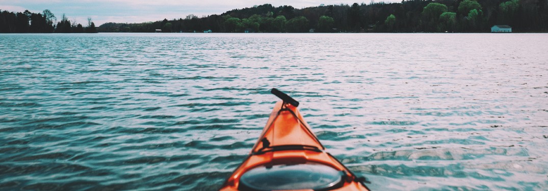 front end of kayak in lake with trees in distance