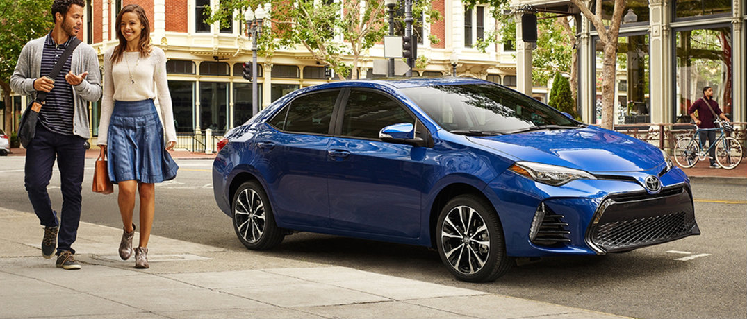 Couple walking away from their parked blue 2018 Toyota Corolla