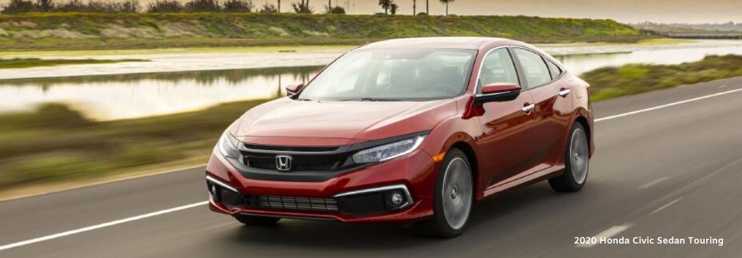 2020 Honda Civic Sedan Touring driving in front of river with palm trees and sky in background from exterior front driver side view