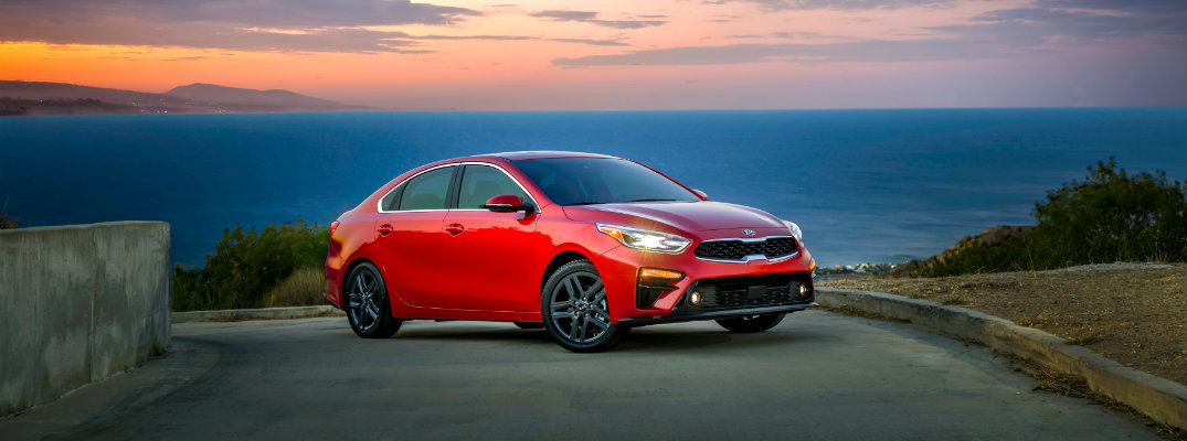 2019 Kia Forte parked by a stone wall and ocean at sunset