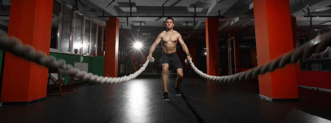 Man in gym working out using battle ropes