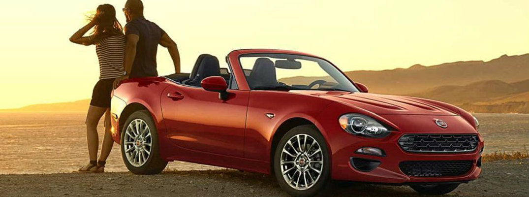 Two people sitting on trunk of 2018 Fiat 124 Spider