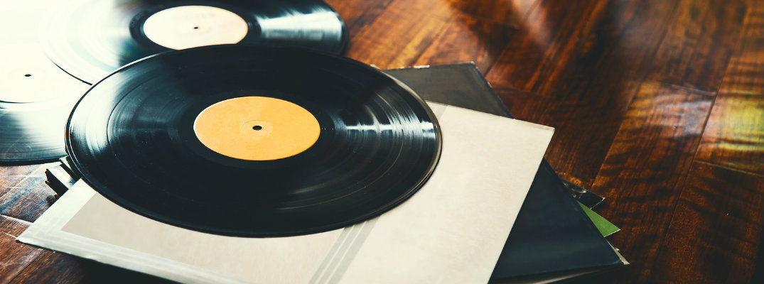 Two vinyl records positioned by their cases on wood table