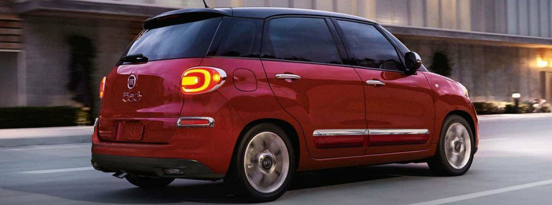 Profile view of red 2018 Fiat 500L driving down city road