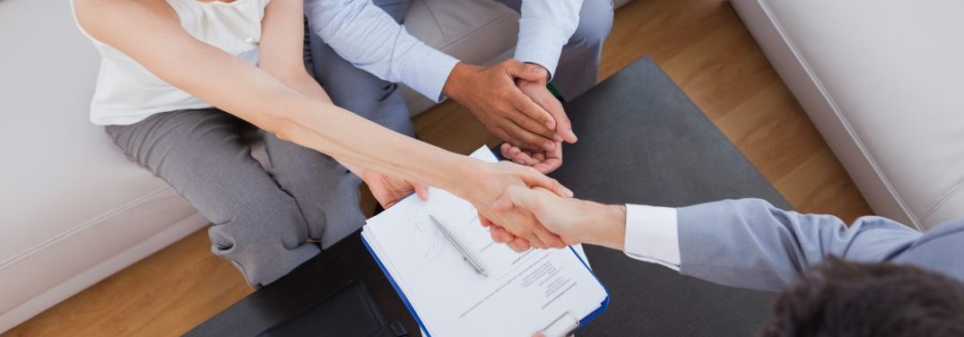 People shaking hands after filling out paperwork that is on a table